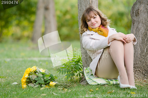 Image of The girl at the tree with a bouquet of yellow roses
