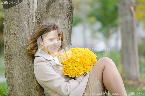 Image of Cute little girl with yellow roses against a tree
