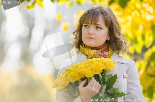 Image of Sad girl with a bouquet of yellow roses
