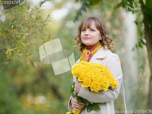 Image of Girl on nature with a bouquet of yellow roses