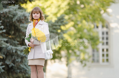 Image of Cute little girl with a bouquet of yellow roses walks in the park