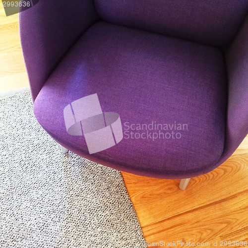 Image of Fashionable purple armchair on wooden floor