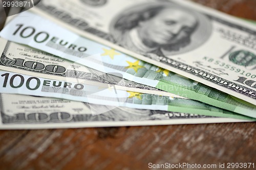 Image of packs of dollars and euro money on wooden background