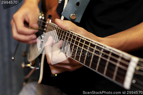 Image of electric guitar close-up with fingers playing it