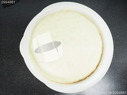 Image of Proven dough in a white plastic bowl on black table