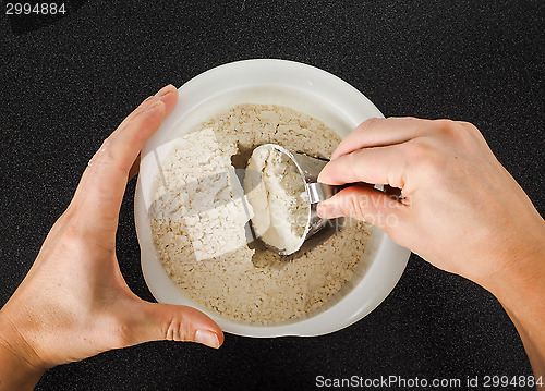 Image of Person using a measurement tool in a bowl of wheat flour