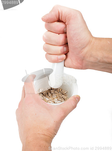 Image of Person crushing brown sugar cubes in a white marble mortar