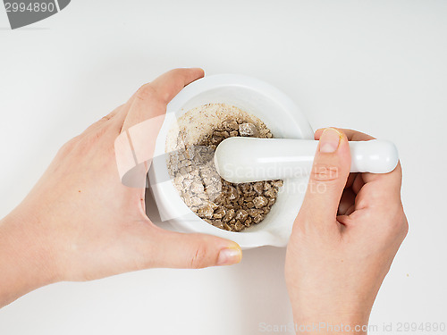 Image of Person crushing brown sugar in a white marble mortar