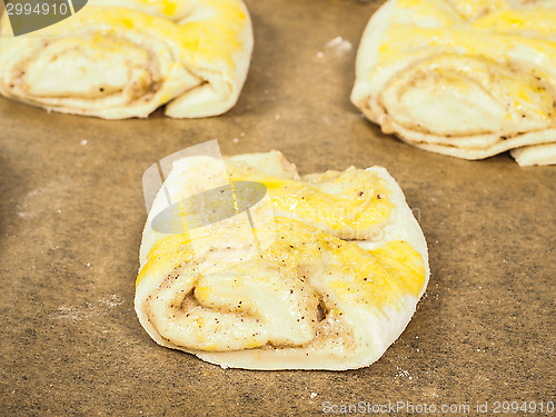 Image of Plaited cinnamon rolls on baking paper with egg wash