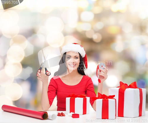 Image of smiling woman in santa helper hat packing gifts