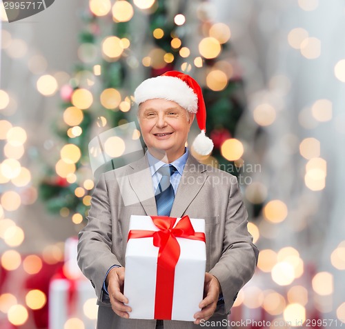 Image of smiling man in suit and santa helper hat with gift