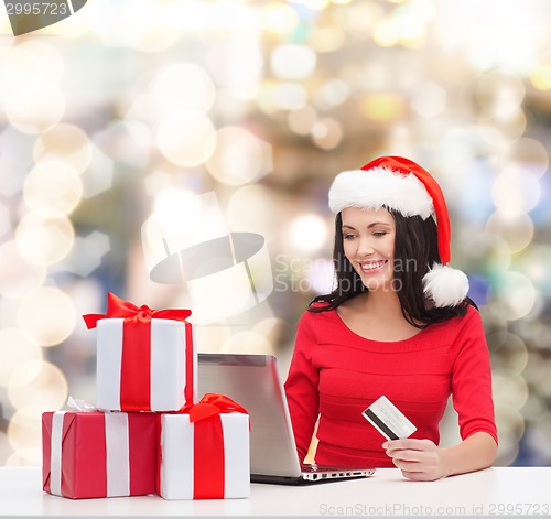 Image of smiling woman with gifts, laptop and credit card