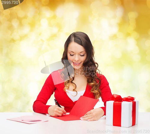 Image of smiling woman with gift box writing letter