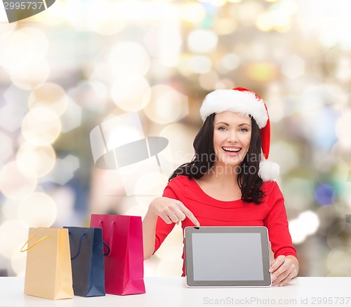 Image of smiling woman in santa hat with bags and tablet pc