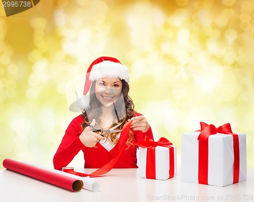 Image of smiling woman in santa helper hat packing gift box