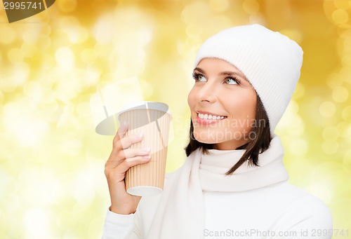 Image of smiling young woman in winter clothes with cup