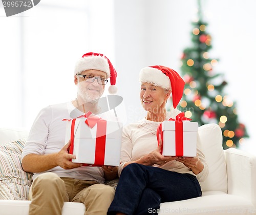 Image of happy senior couple in santa hats with gift boxes