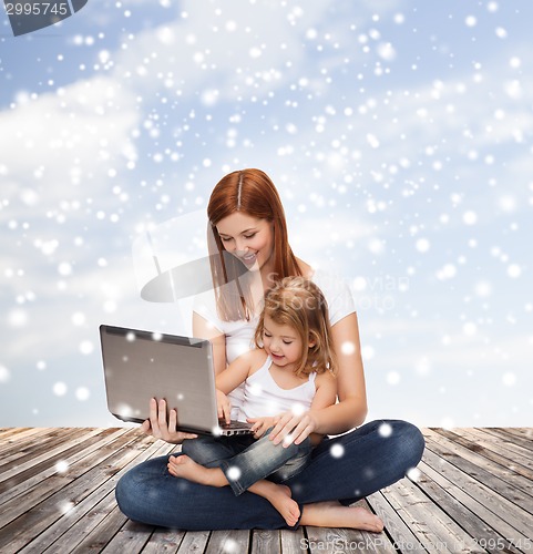 Image of happy mother with little girl and laptop