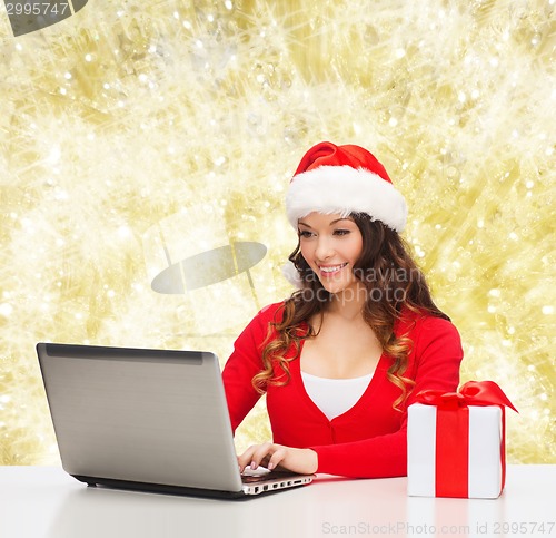 Image of smiling woman with gift box and laptop