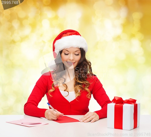 Image of smiling woman with gift box writing letter