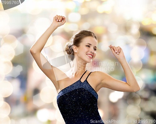 Image of smiling woman dancing with raised hands