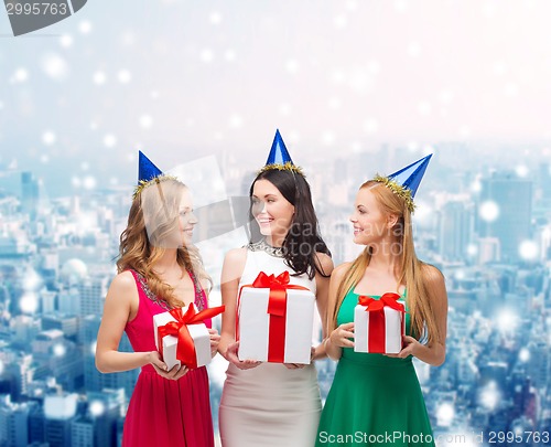 Image of smiling women in party caps with gift boxes