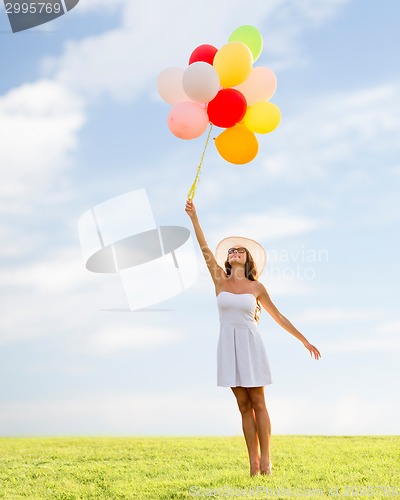 Image of smiling young woman in sunglasses with balloons