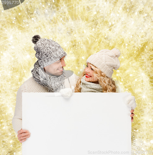 Image of smiling couple in winter clothes with white board