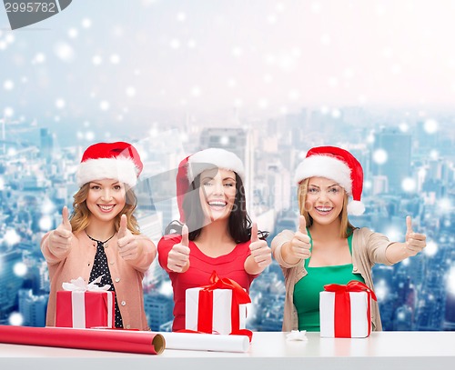Image of smiling women in santa helper hats packing gifts