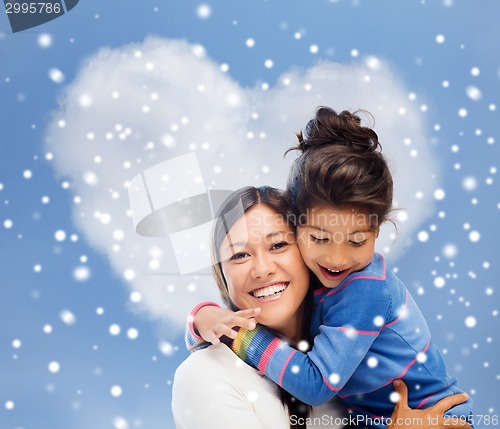 Image of smiling little girl and mother hugging indoors