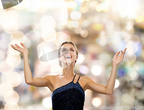 Image of smiling woman raising hands and looking up