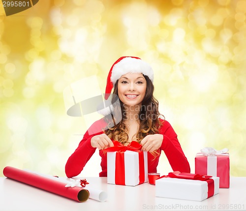 Image of smiling woman in santa helper hat packing gifts