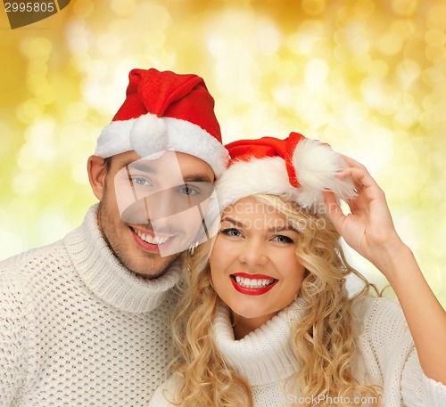 Image of smiling couple in sweaters and santa helper hats