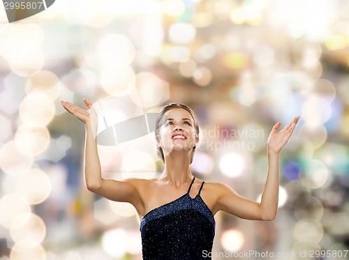 Image of smiling woman raising hands and looking up