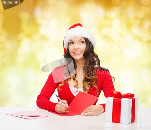 Image of smiling woman with gift box writing letter