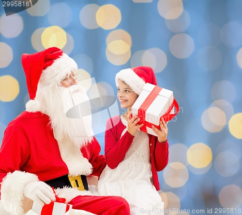 Image of smiling little girl with santa claus and gifts