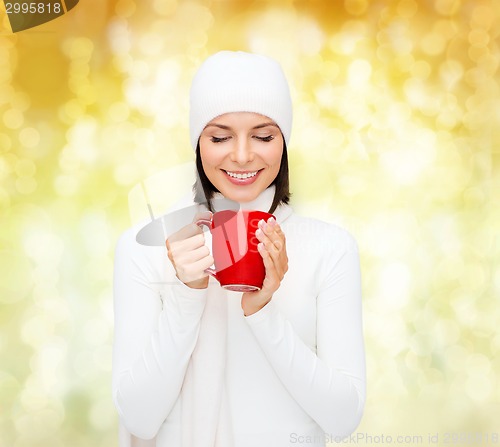 Image of smiling young woman in winter clothes with cup