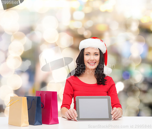Image of smiling woman with shopping bags and tablet pc