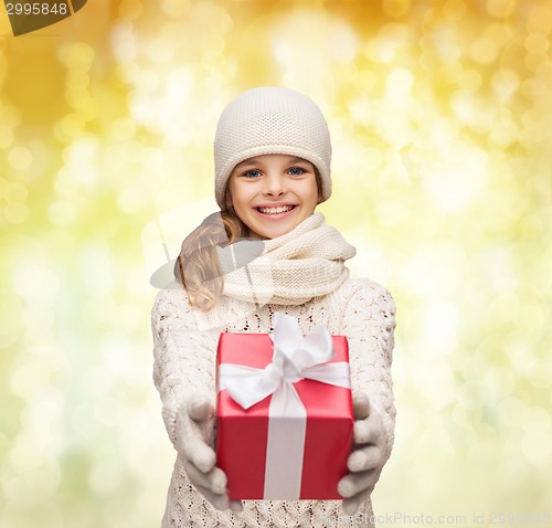 Image of dreaming girl in winter clothes with gift box