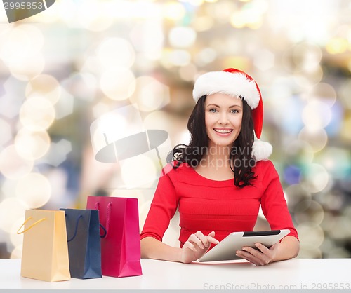 Image of smiling woman with shopping bags and tablet pc