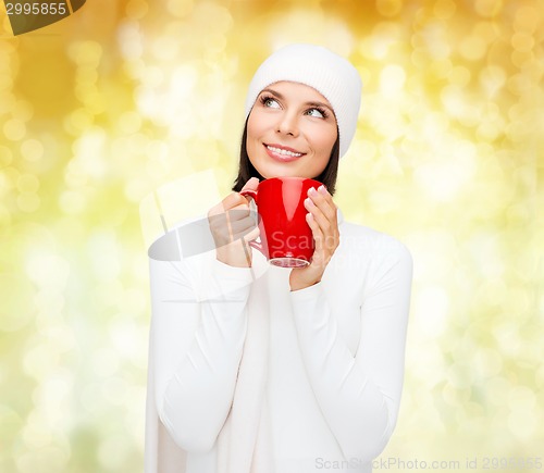 Image of smiling young woman in winter clothes with cup