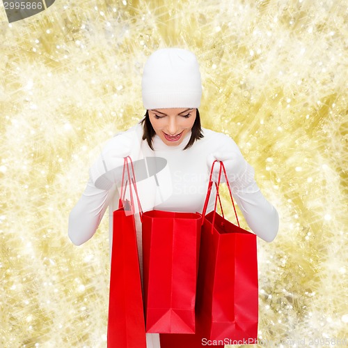 Image of smiling young woman with red shopping bags