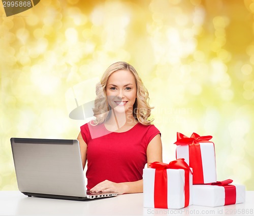 Image of smiling woman in red shirt with gifts and laptop