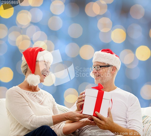 Image of happy senior couple with gift box at home