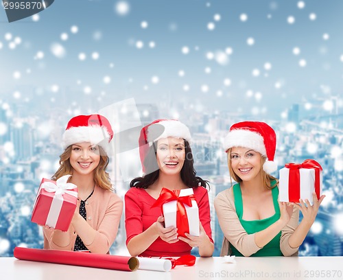 Image of smiling women in santa helper hats packing gifts