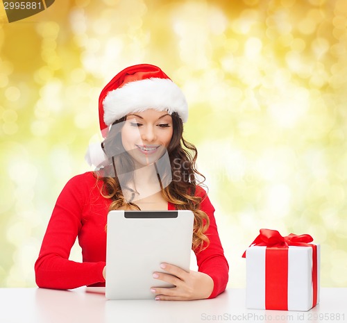 Image of smiling woman in santa hat with gift and tablet pc