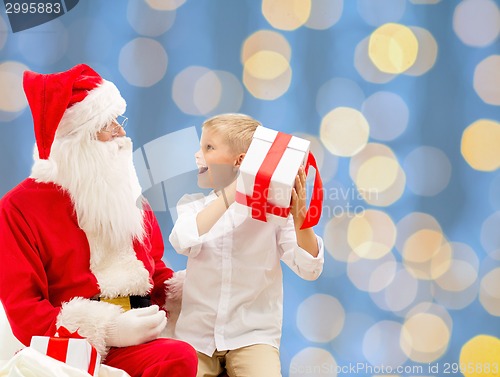 Image of smiling little boy with santa claus and gifts