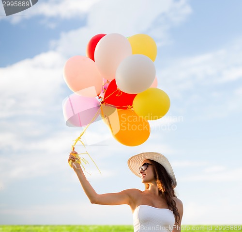 Image of smiling young woman in sunglasses with balloons