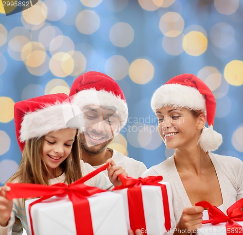 Image of happy family in santa helper hats with gift boxes