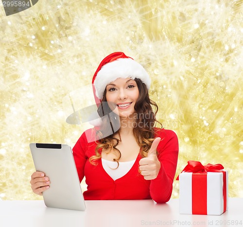 Image of smiling woman in santa hat with gift and tablet pc